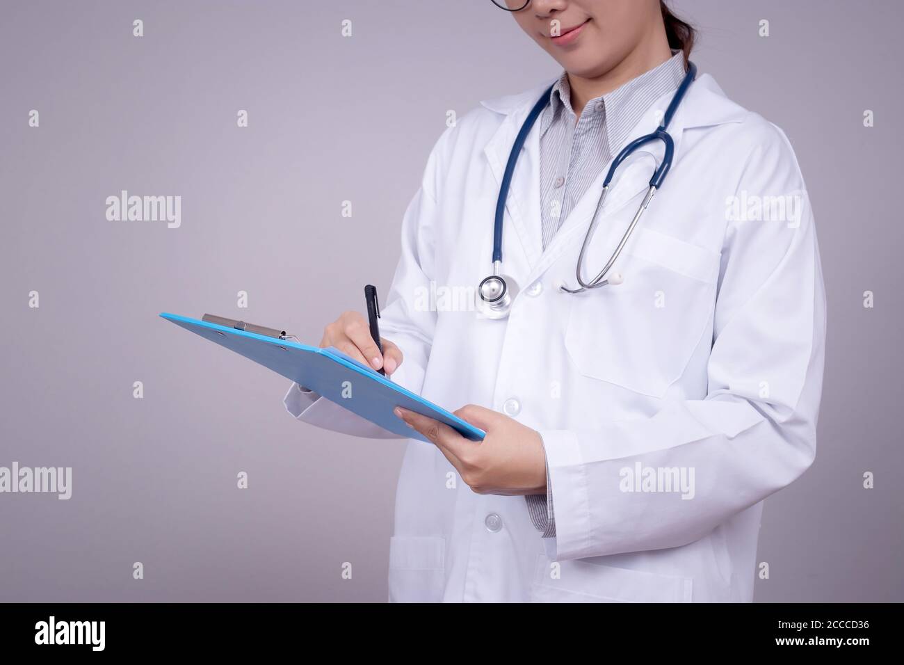 Concetto sano : giovane medico asiatico che scrive sulla clipboard per la cartella del paziente, faccia anonima. Bella Asia modello femminile nei suoi 30 Foto Stock