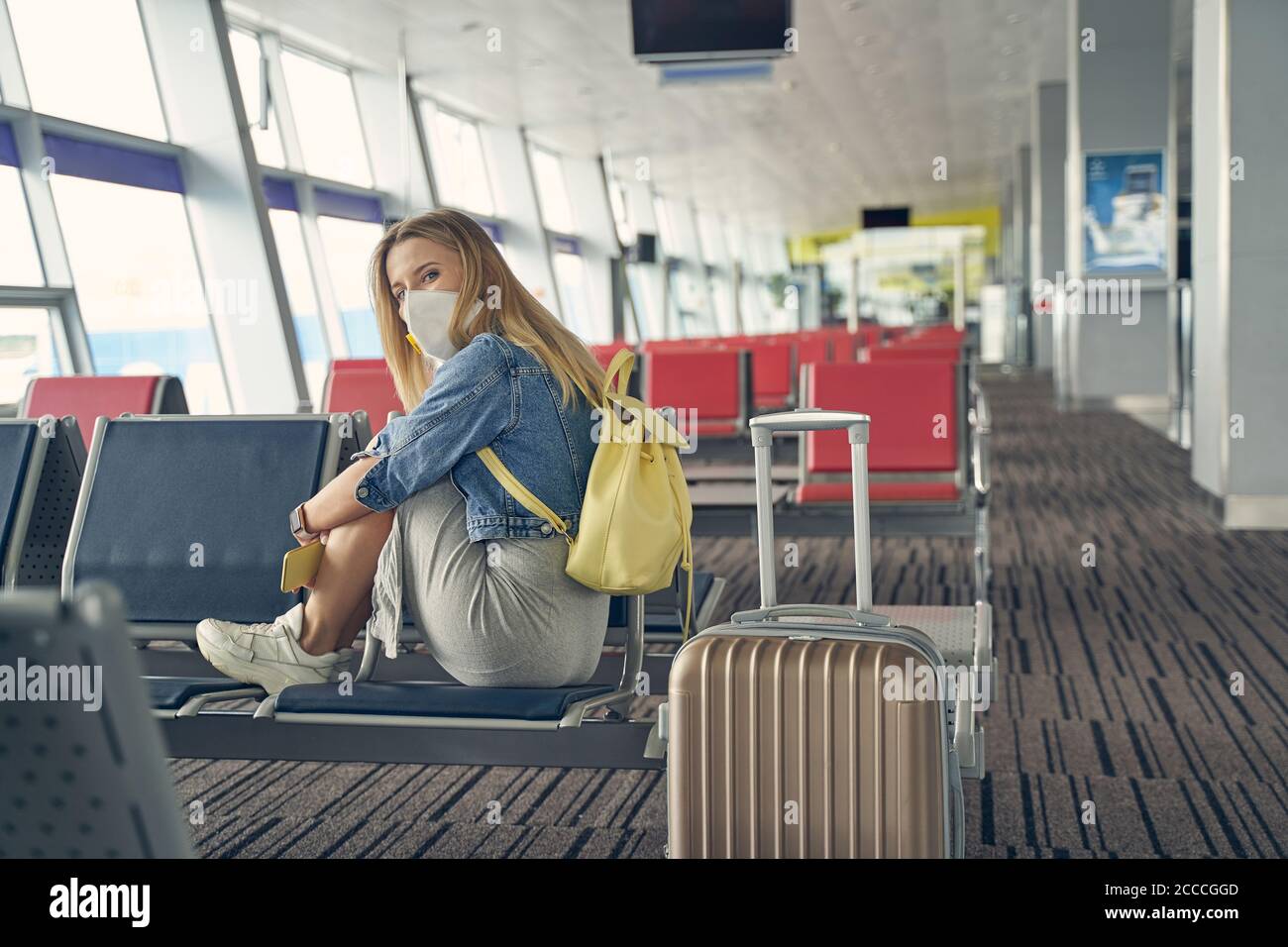 Annoiata giovane donna in attesa del suo volo Foto Stock