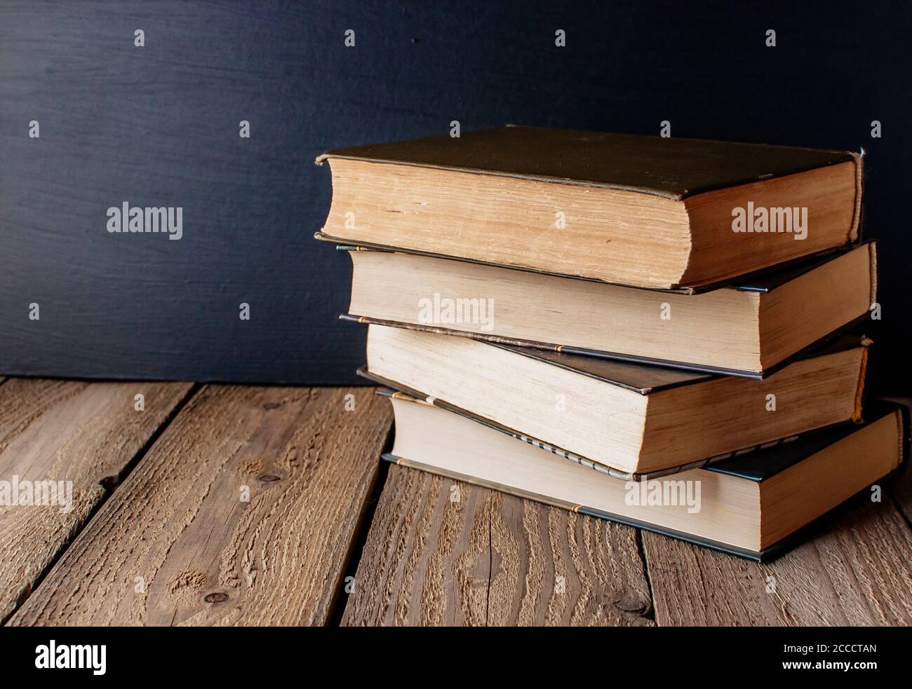 libri accatastati su un tavolo di legno in uno stile rustico sullo sfondo una lavagna scuola. Il concetto di benvenuto a scuola. Copia spazio Foto Stock