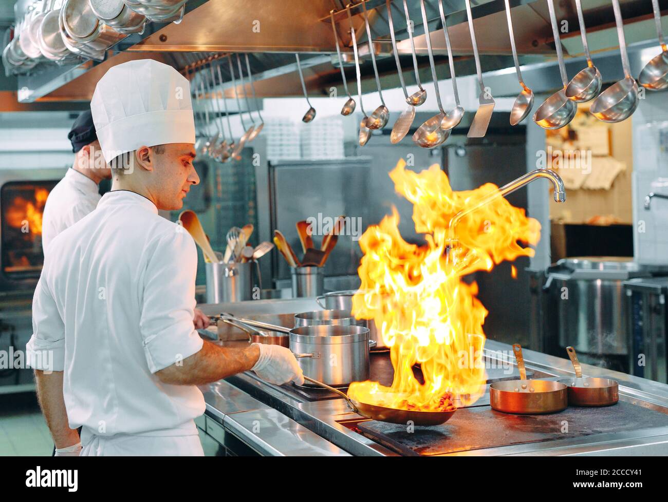 Cucina moderna. I cuochi preparano pasti sul fornello nella cucina del ristorante o albergo. Il fuoco in cucina. Foto Stock
