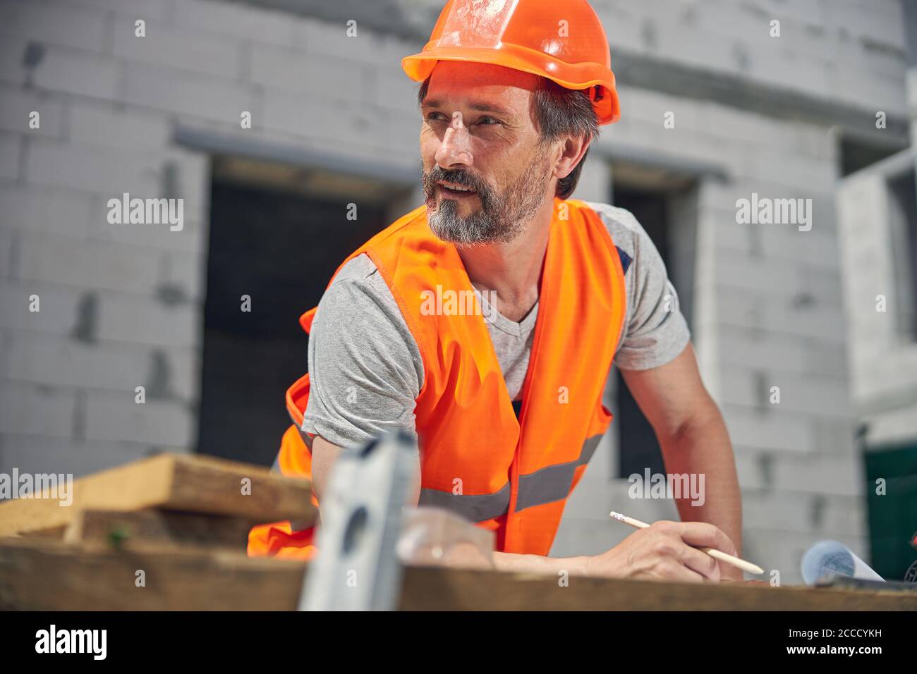 Pensieroso costruttore poggiando il gomito sul tavolo Foto Stock
