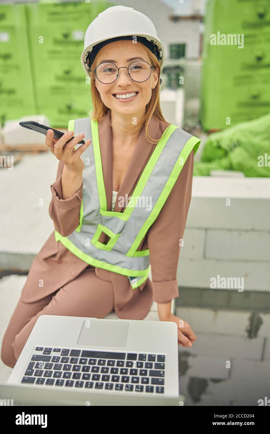 Donna di fronte felice con un cellulare sorridente alla macchina fotografica Foto Stock