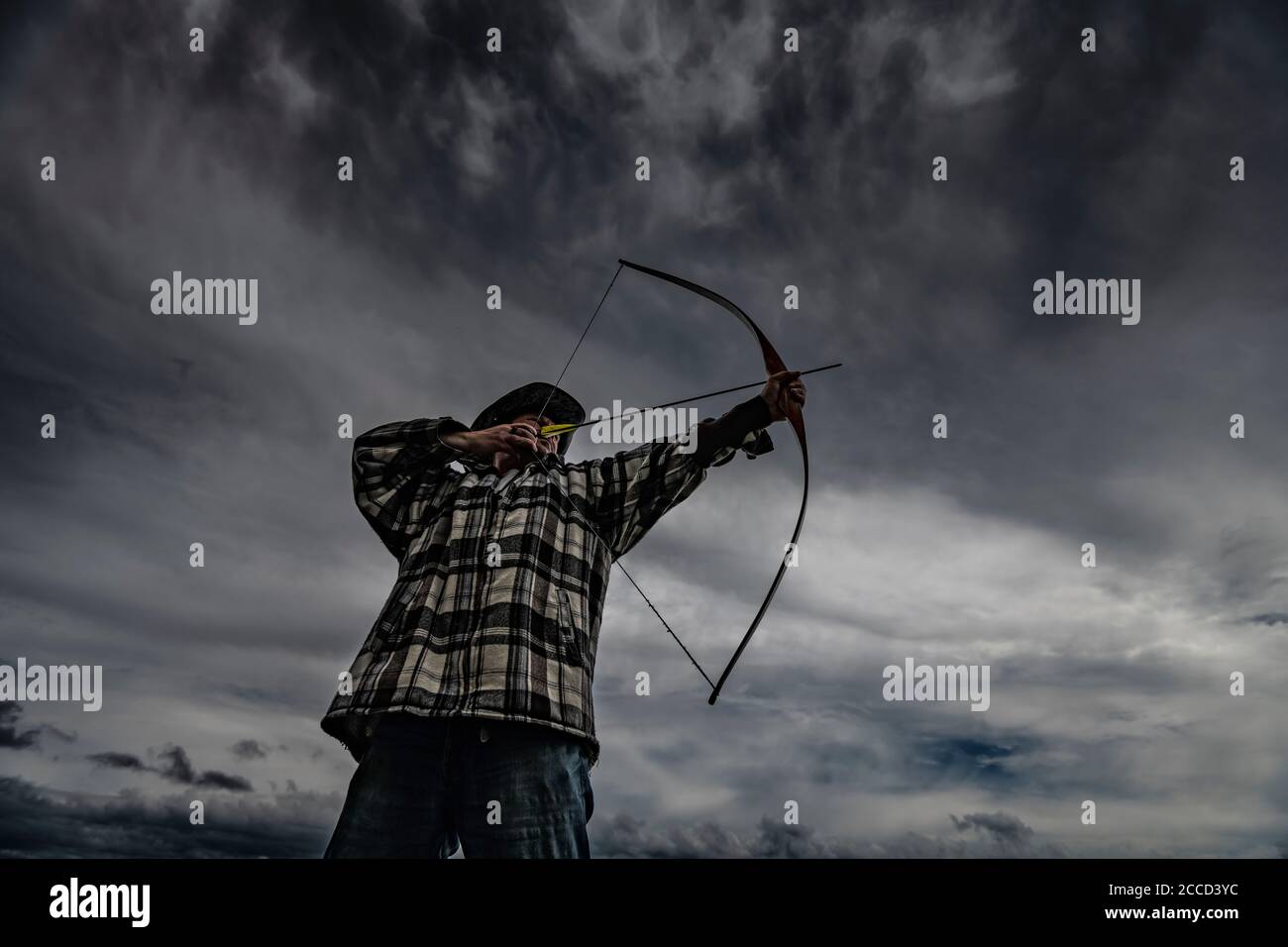 Cacciatore ricreativo in cappello tiro longbow. Tiro naturale di tiro con l'arco. Foto Stock