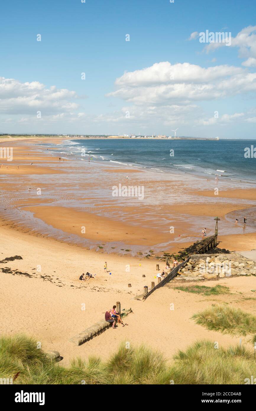 Persone che godono di sole estivo sulla spiaggia a nord di Seaton Sluice, Northumberland, Inghilterra, Regno Unito Foto Stock
