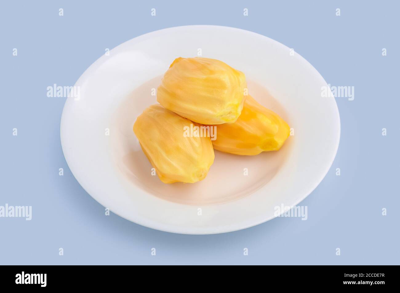 Jackfruit tropicale giallo fresco maturo su piatto bianco isolato su sfondo azzurro, percorso di ritaglio incluso. Foto Stock