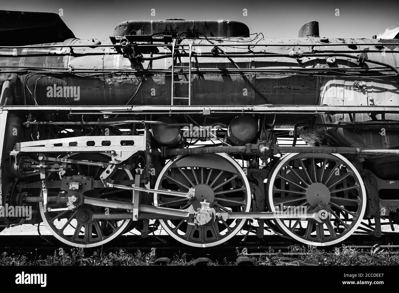 Grande locomotiva a vapore d'epoca, dettaglio ruota in acciaio verniciata di rosso da vicino. Treno a vapore a carbone su un siding. Macchinario ferroviario pesante gigantesco classico Foto Stock