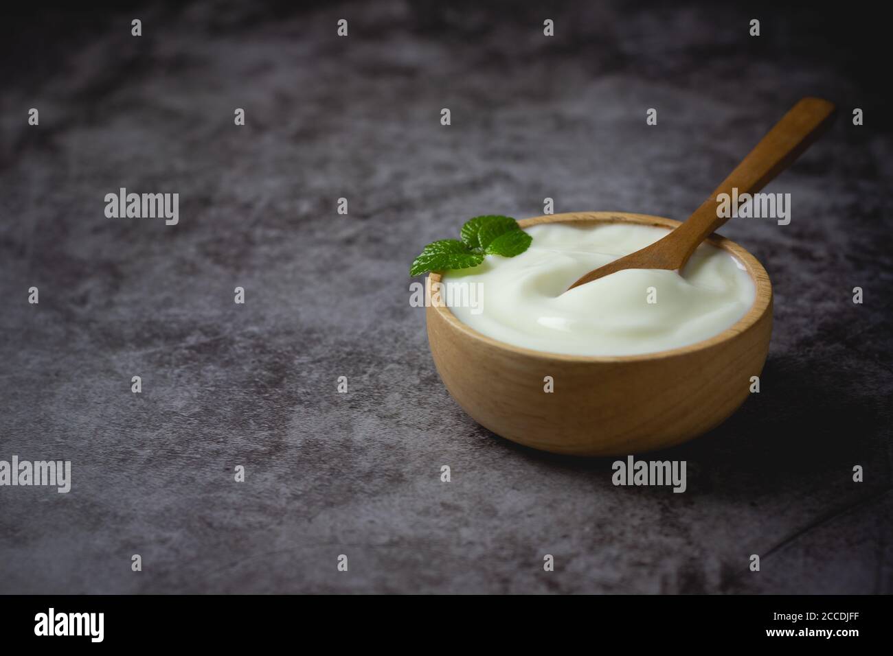 Yogurt bianco in ciotola di legno sul tavolo Foto Stock