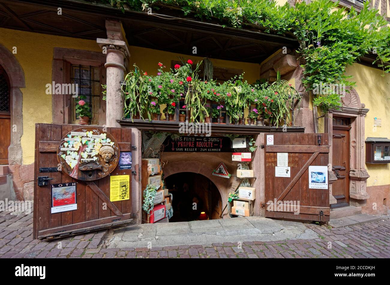 Negozio seminterrato, ampie porte doppie, balcone con fiori, viti verdi, vecchio edificio, scena stradale; Città Vecchia, 15-18 secoli; Alsazia; Europa; Riquewihr; Foto Stock