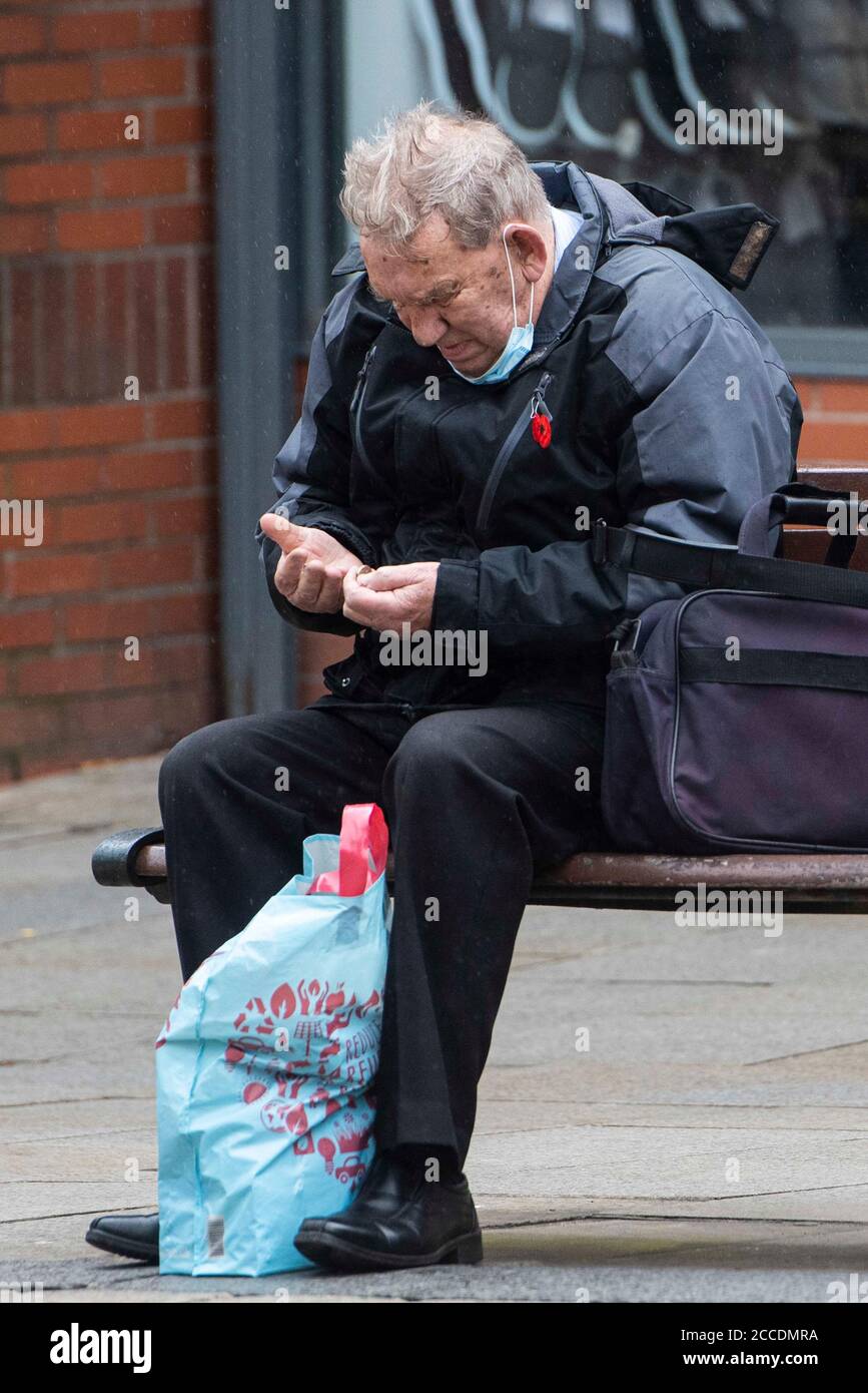 Bagnati e cupi iniziano la giornata per i membri del pubblico nel centro di Oldham, che si trova sul bordo della serratura. Foto Stock