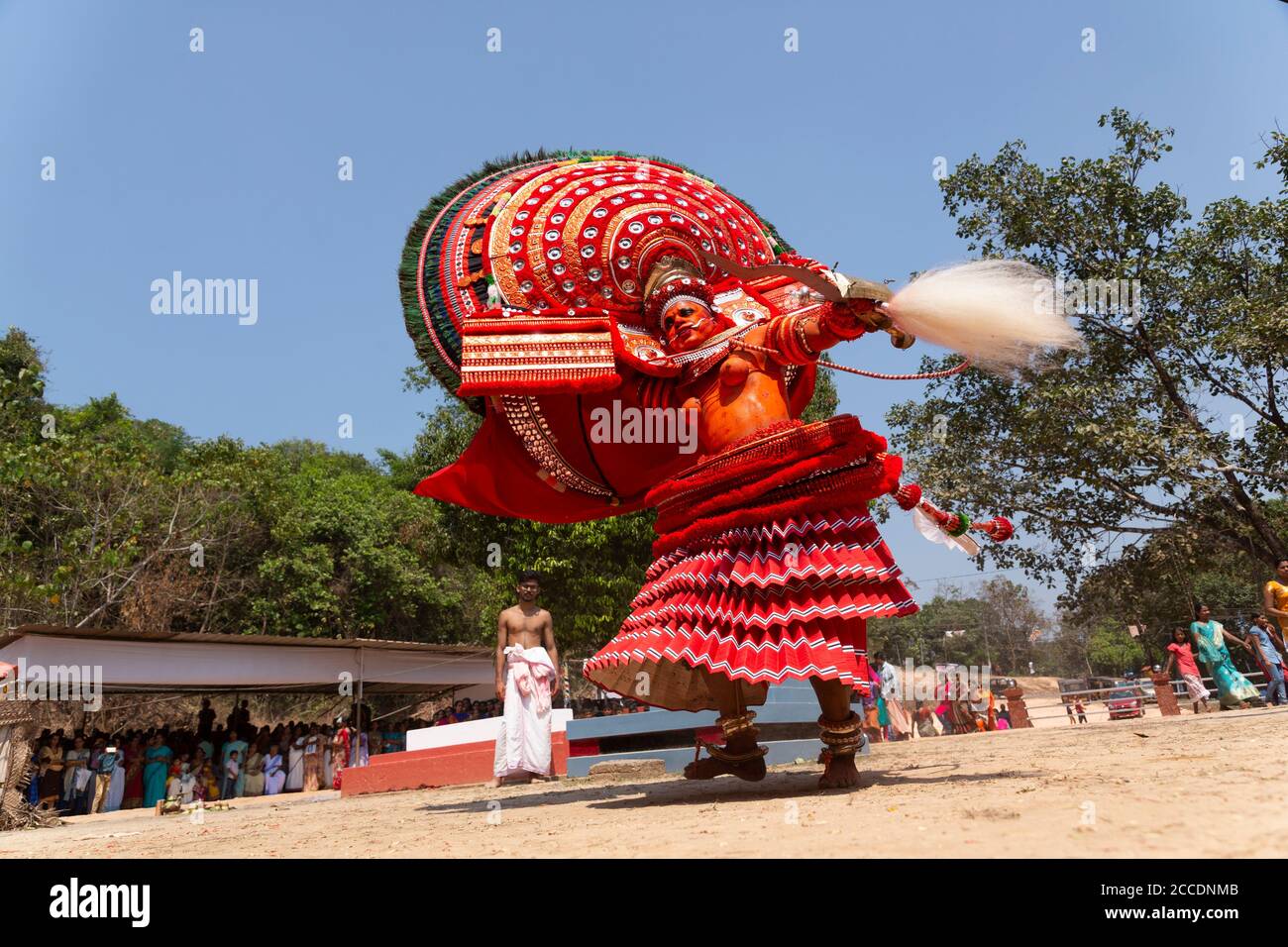 Tradizionale esecutore di Theyyam adornato con elaborati costumi e trucco durante una danza rituale nel Kerala, in India. Cattura il vivace patrimonio culturale Foto Stock