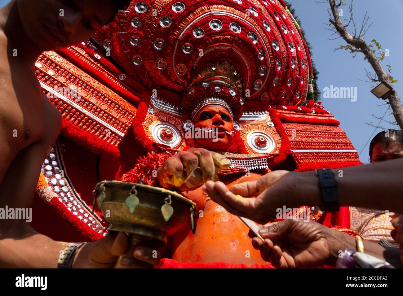 Tradizionale esecutore di Theyyam adornato con elaborati costumi e trucco durante una danza rituale nel Kerala, in India. Cattura il vivace patrimonio culturale Foto Stock