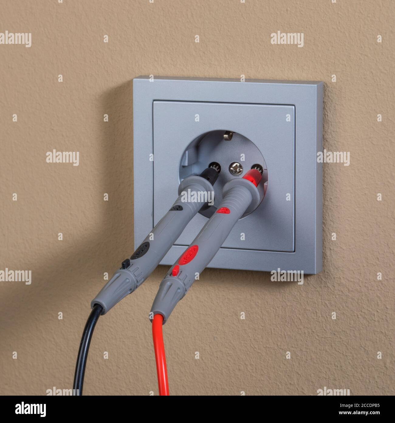 misurazione della tensione nella moderna spina a muro con rosso e nero lead Foto Stock