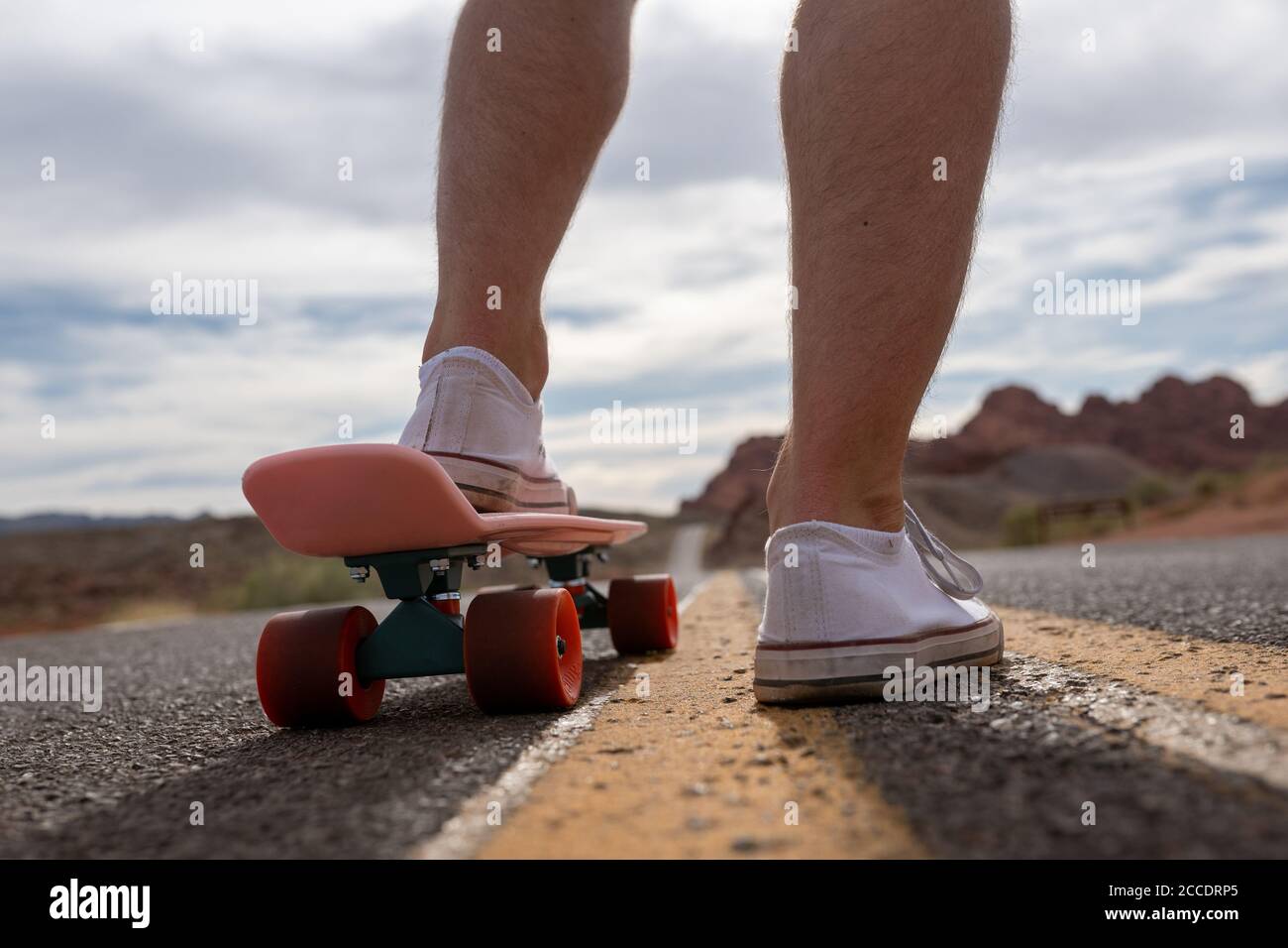 Un uomo pronto a decollo sulla strada aperta su uno skateboard elettrico in una giornata luminosa e soleggiata Foto Stock