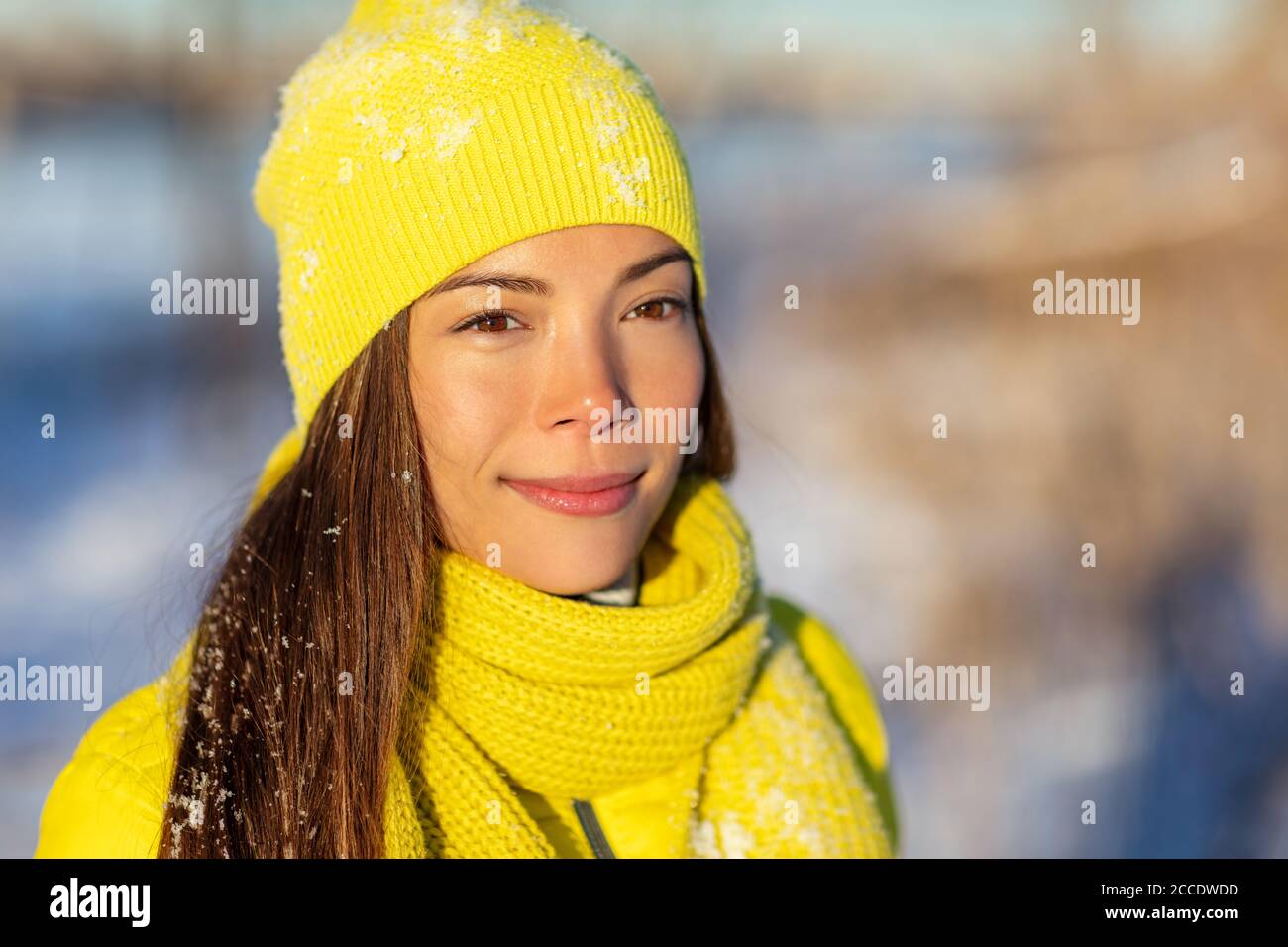 Donna invernale Asian beauty ragazza che cammina nella neve all'aperto con cappello in maglia di beanie giallo e sciarpa per la protezione dal gelo freddo. Donna felice multirazziale Foto Stock