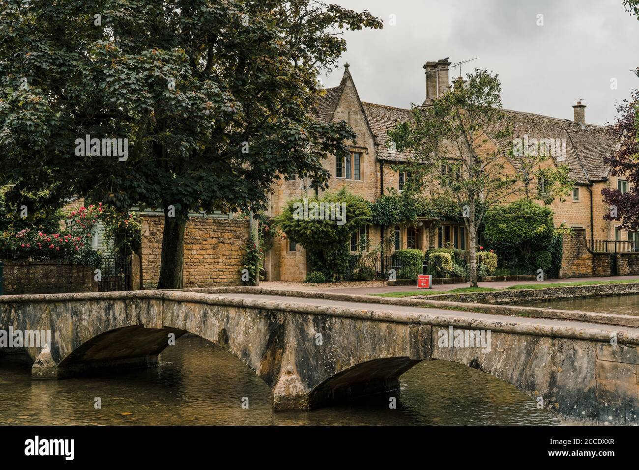Bourton-on-the-Water, Regno Unito - 10 luglio 2020: Piccolo ponte in pietra sul fiume Windrush a Bourton-on-the-Water, un famoso villaggio nelle Cotswolds rurali Foto Stock