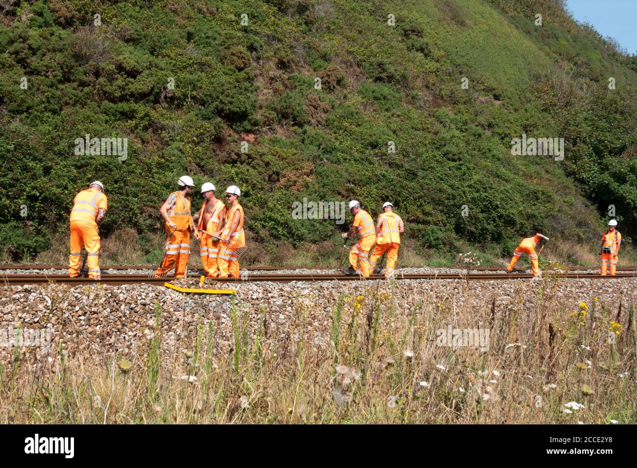 Un gruppo, o una banda, o Netwok Rail, lavoratori che svolgono lavori di manutenzione su una pista ferroviaria in tempo reale. Gli operatori stanno eliminando i detriti dal cingolo Foto Stock