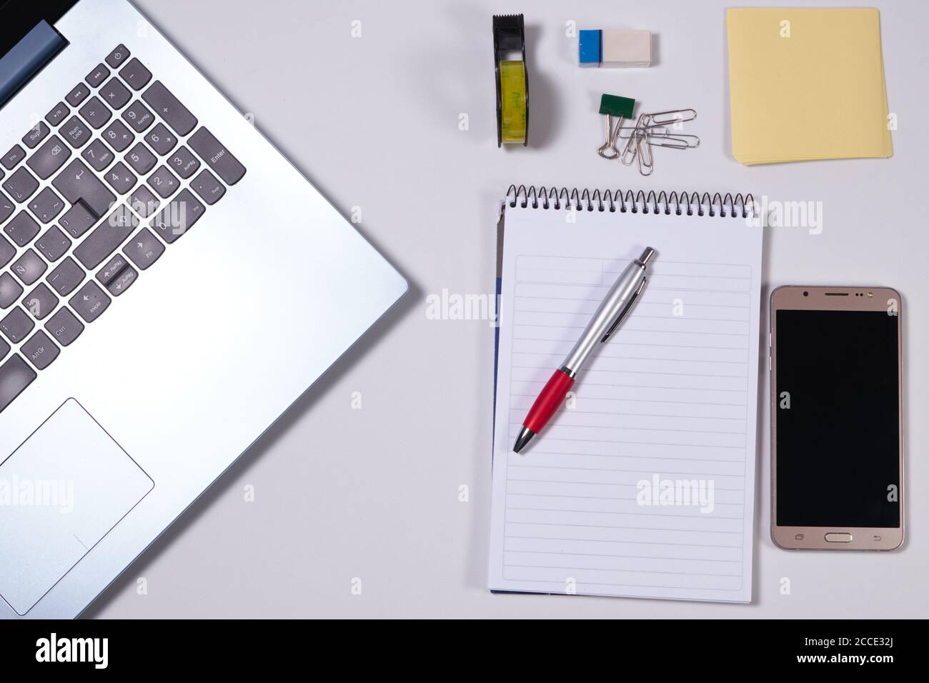 Moderno tavolo da lavoro bianco con computer portatile, smartphone e altri accessori. Vista dall'alto, disposizione piatta. Foto Stock