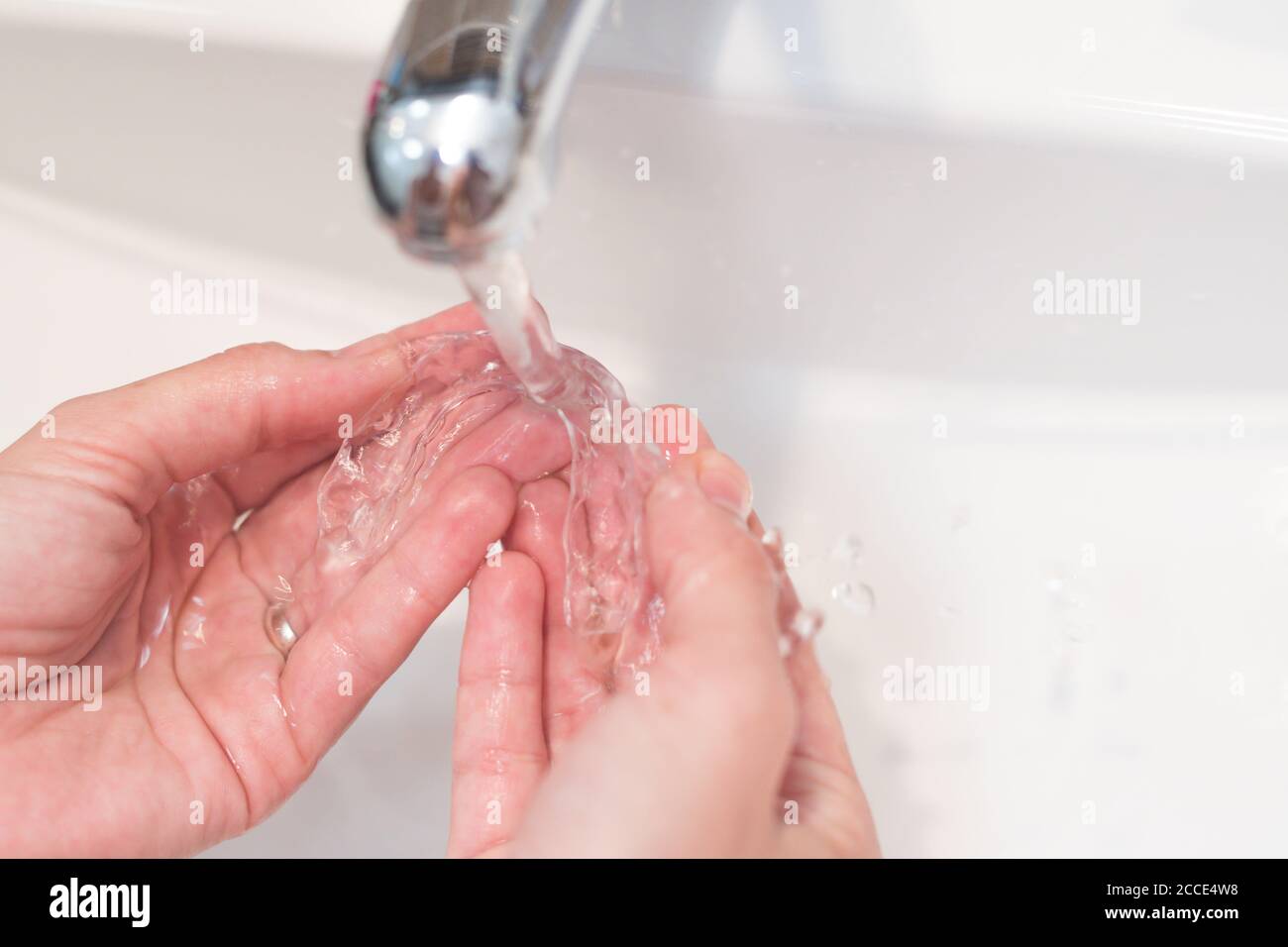 le mani della donna lavano i suoi allineatori invisibili per la correzione dentale con acqua Foto Stock