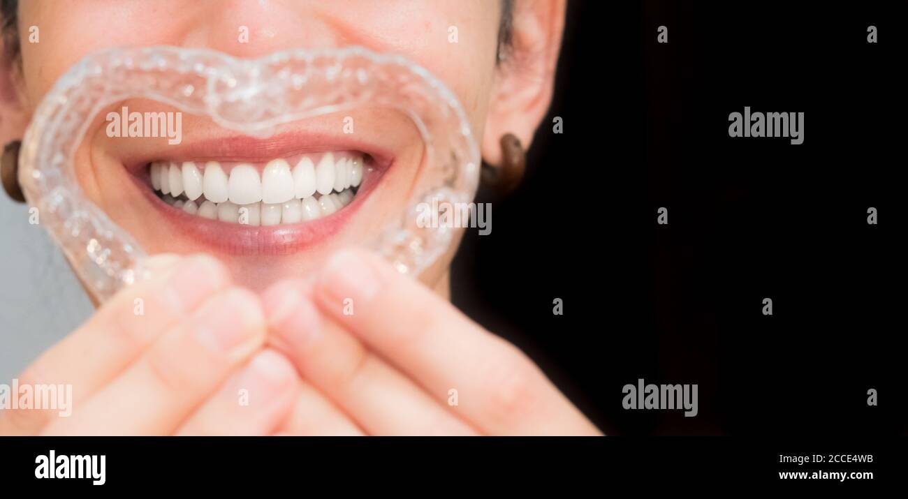 donna sorridente che fa un cuore con i suoi allineatori invisibili per la correzione dentale. ortodontica mobile Foto Stock