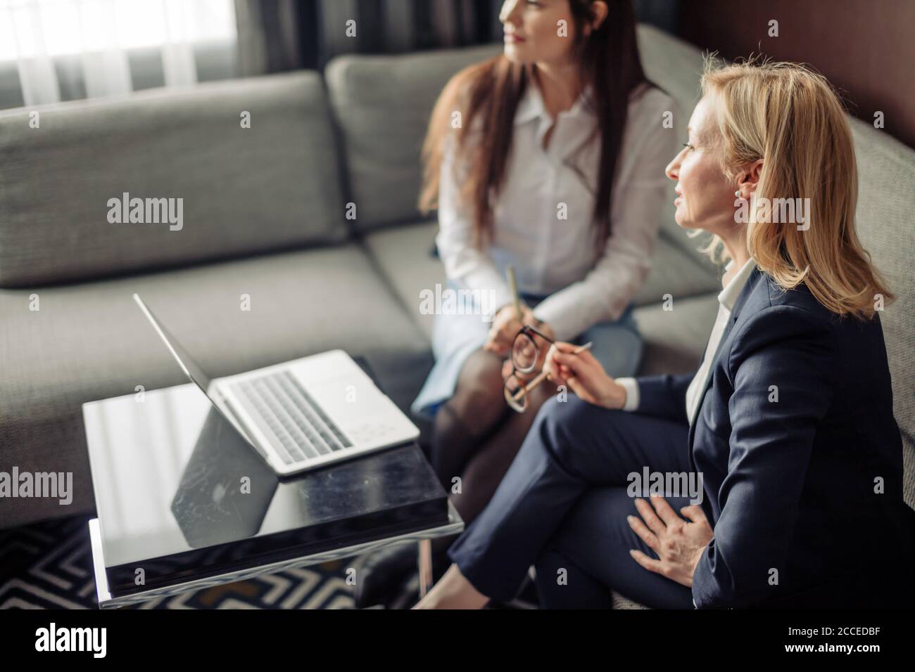 Due colleghi caucasici che lavorano insieme su un progetto aziendale utilizzando un laptop, una donna esecutiva che spiega una nuova idea online al collega in ufficio Foto Stock