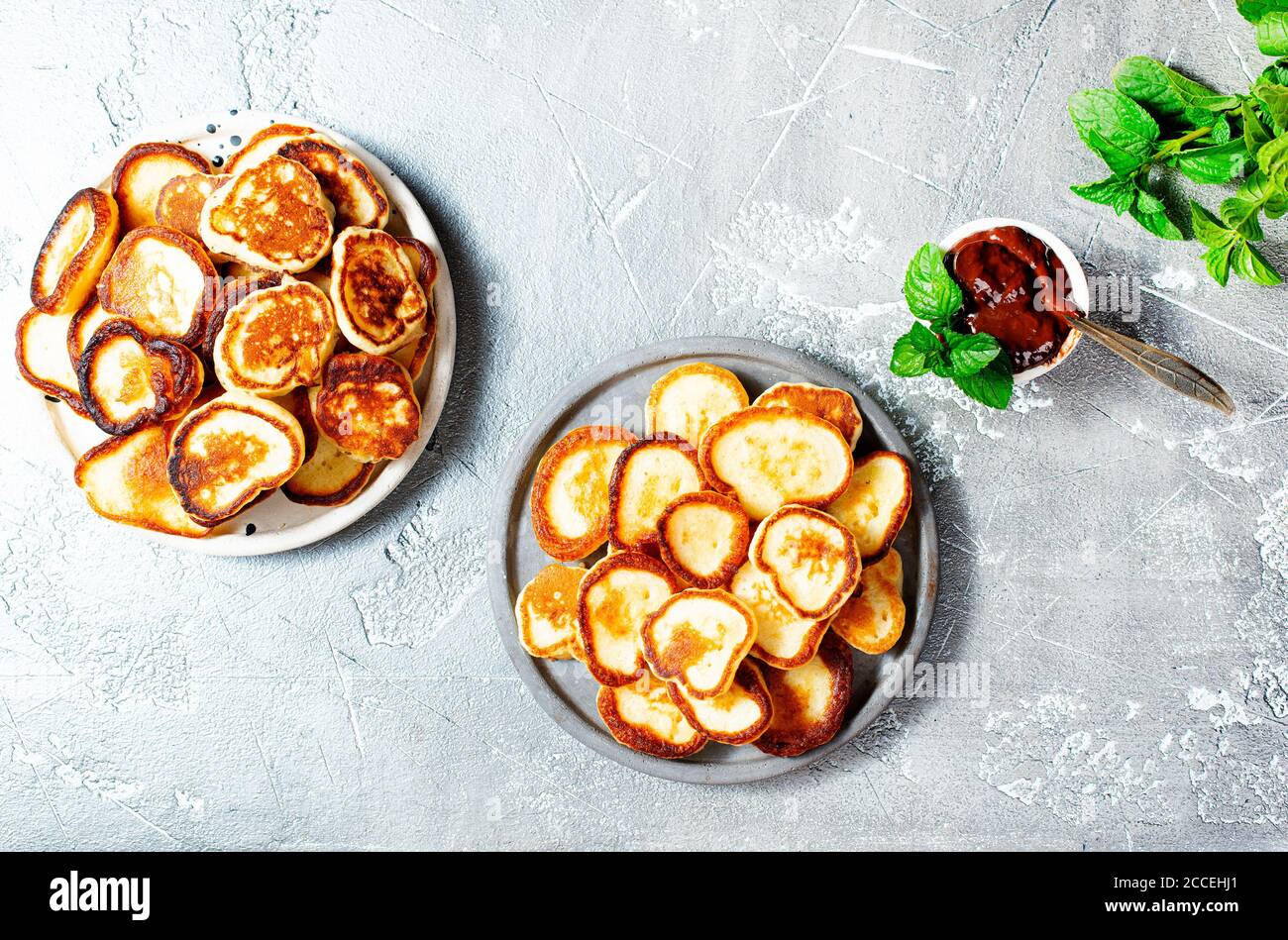 Mini frittelle sul piatto, tavolo con vista dall'alto su sfondo grigio. Foto Stock