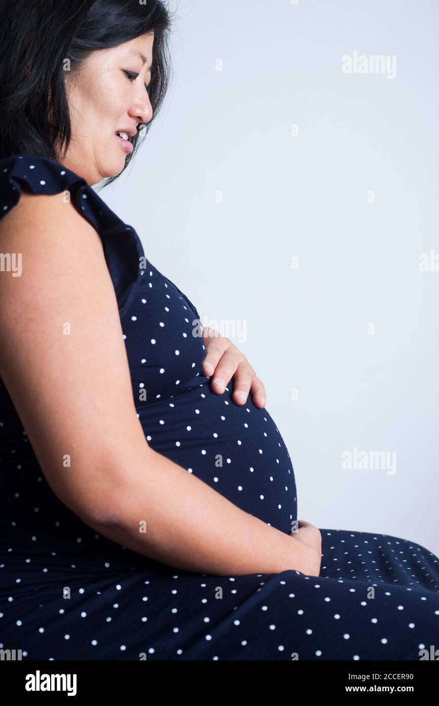 Donna incinta mentre tiene il suo addome Foto Stock