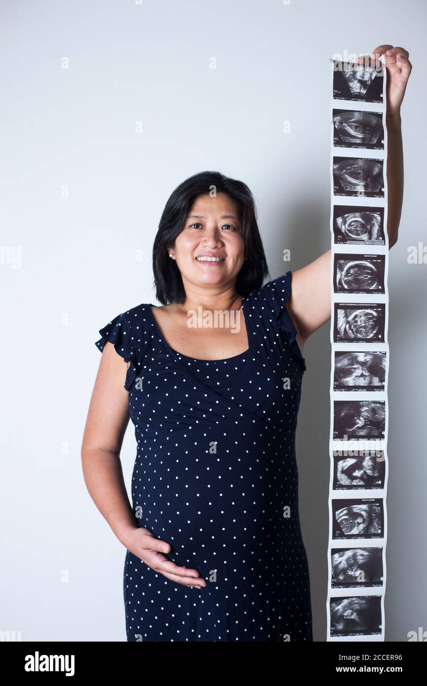 Donna incinta che tiene le scansioni del bambino Foto Stock