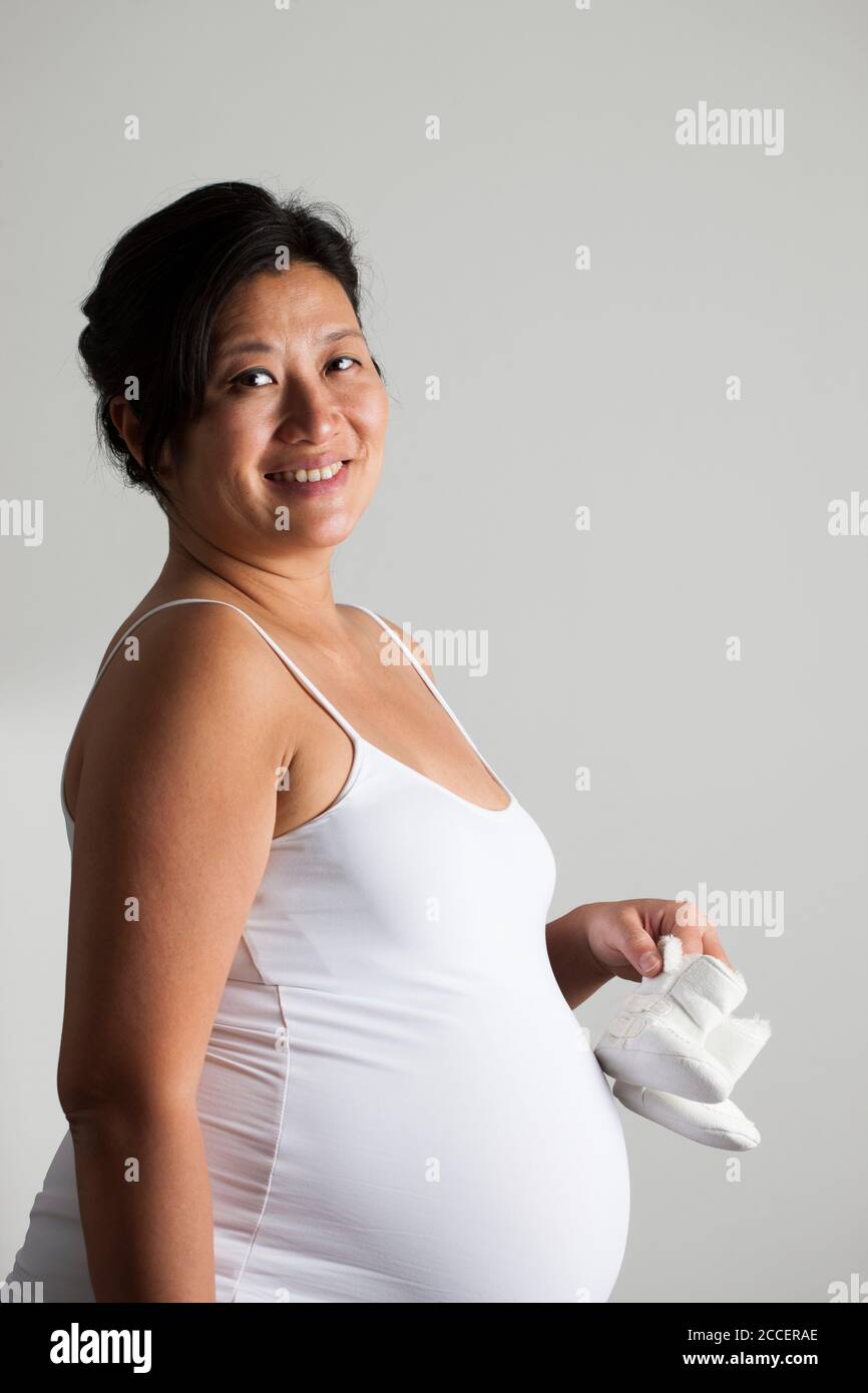Donna incinta azienda scarpe per bambini Foto Stock