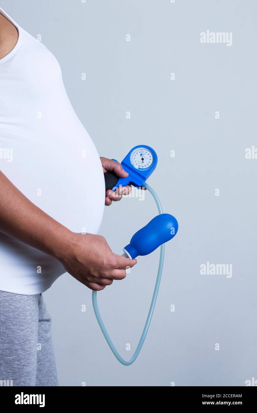 Donna incinta che tiene l'addestratore pelvico del pavimento Foto Stock