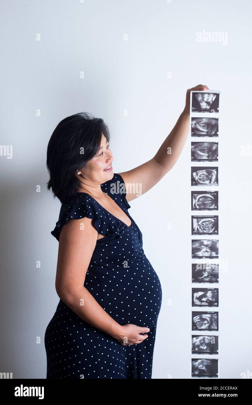 Donna incinta che tiene le scansioni del bambino Foto Stock