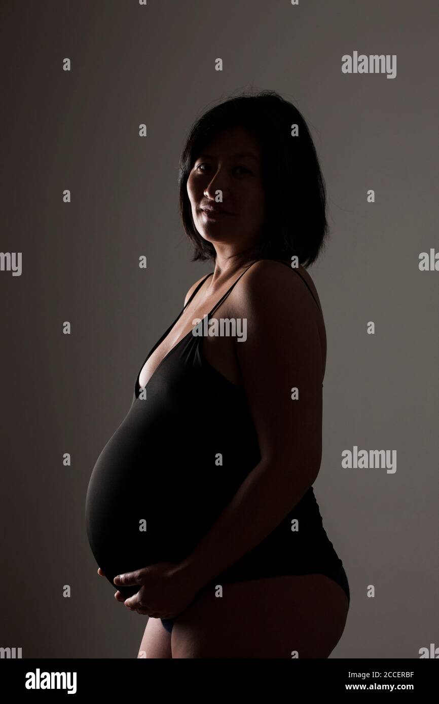 Donna incinta mentre tiene il suo addome Foto Stock