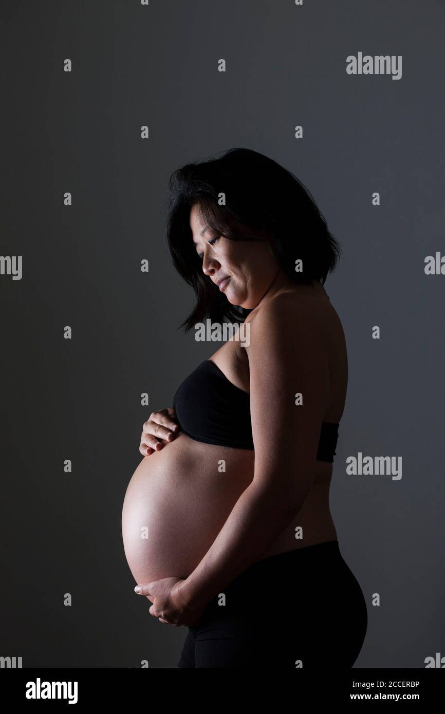 Donna incinta mentre tiene il suo addome Foto Stock