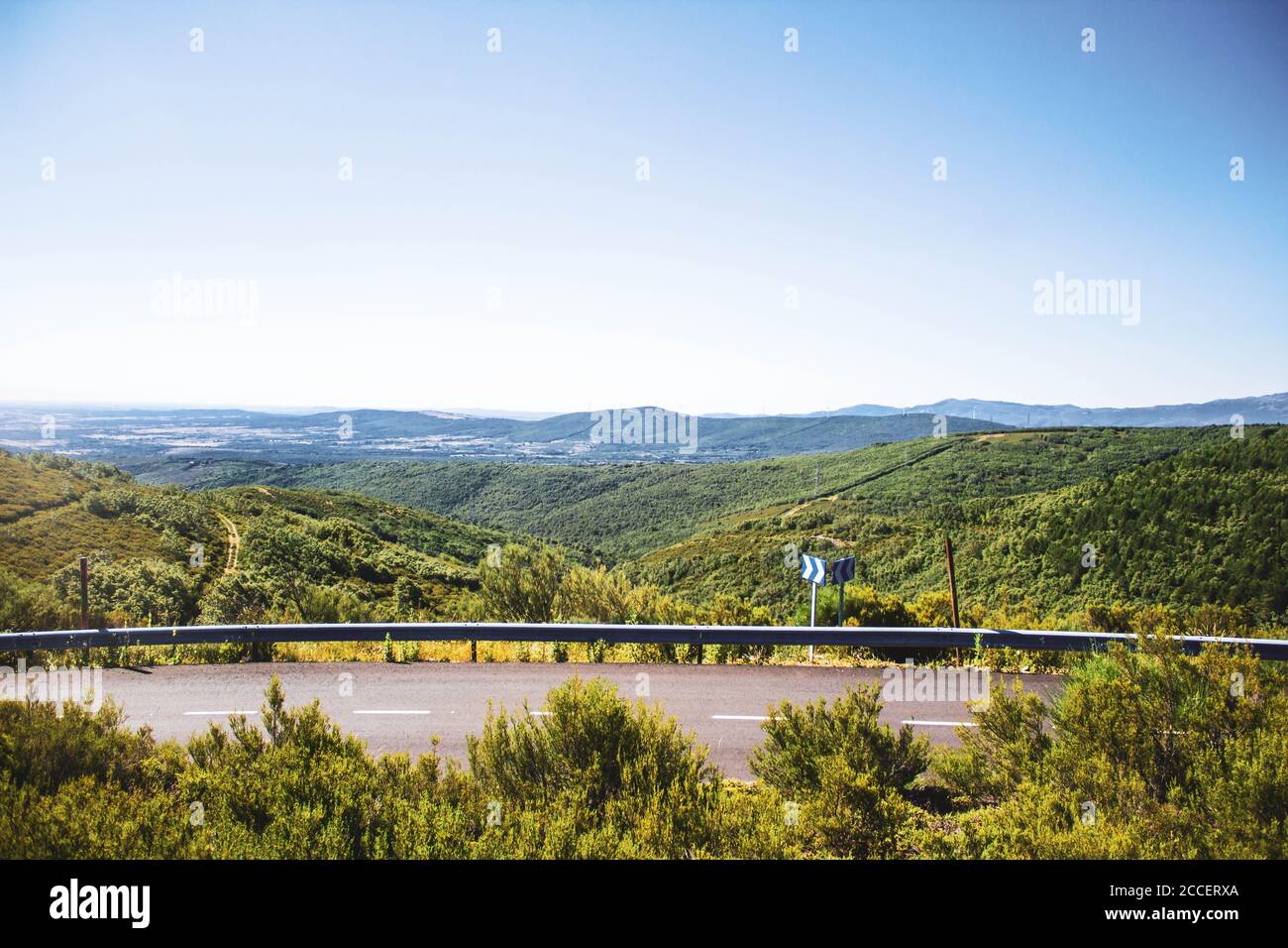 strada che attraversa il paesaggio di foresta e montagne contro il cielo blu Foto Stock