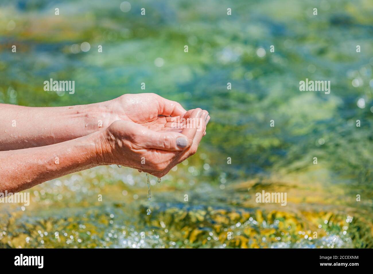 Le mani traggono acqua da un ruscello di montagna Foto Stock