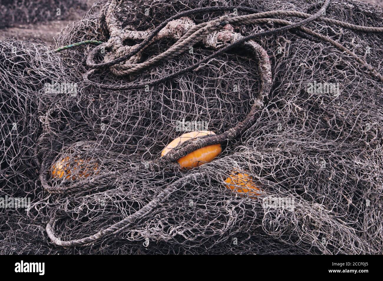 Un mucchio di reti da pesca nere con galleggianti gialli Foto Stock