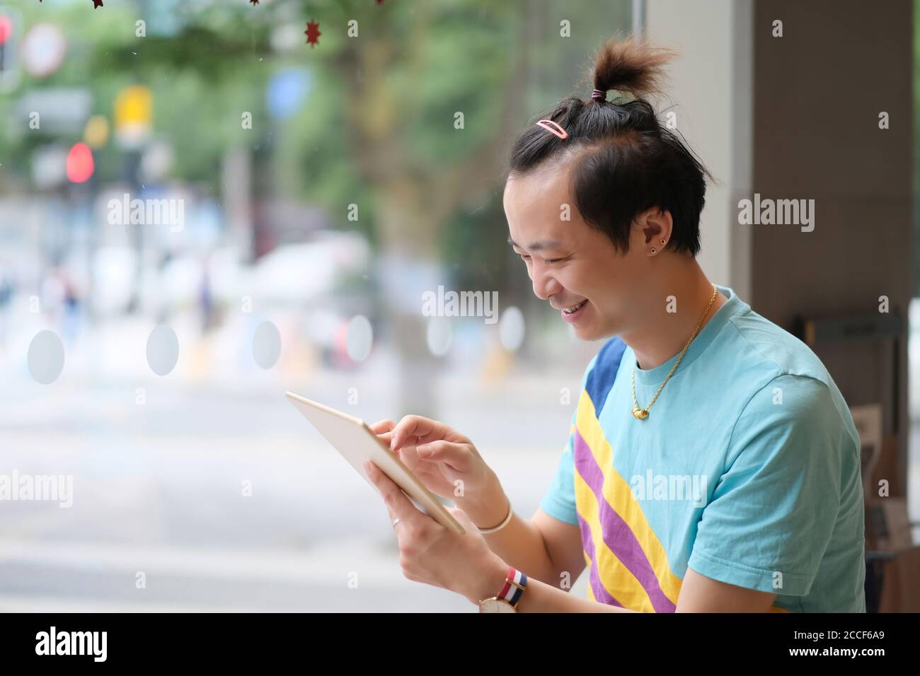 Primo piano un giovane asiatico sorridente, utilizzando un computer tablet al chiuso Foto Stock