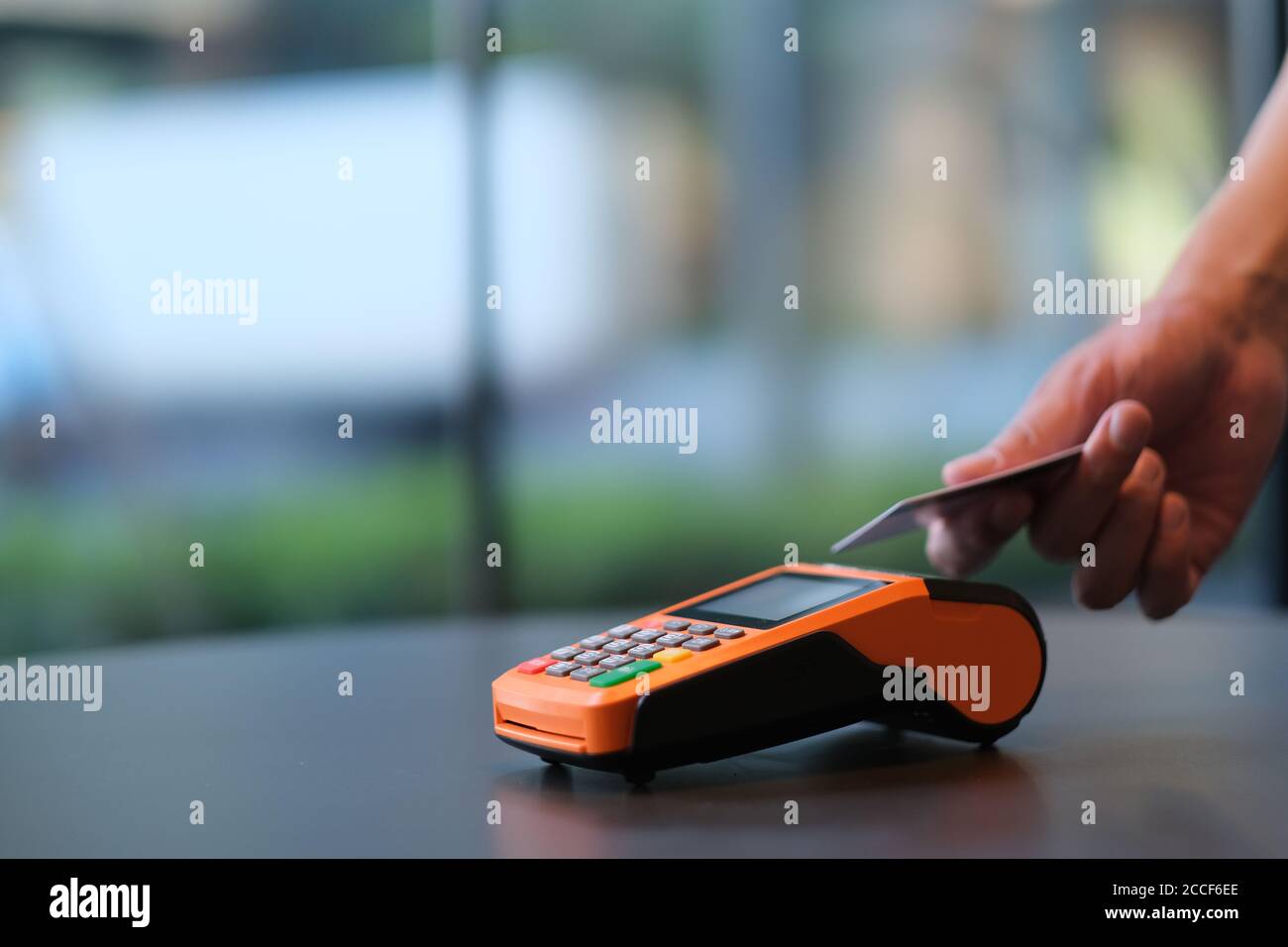 primo piano persone che tengono la carta di credito per pagare sul terminale pos al banco. sfondo sfocato Foto Stock