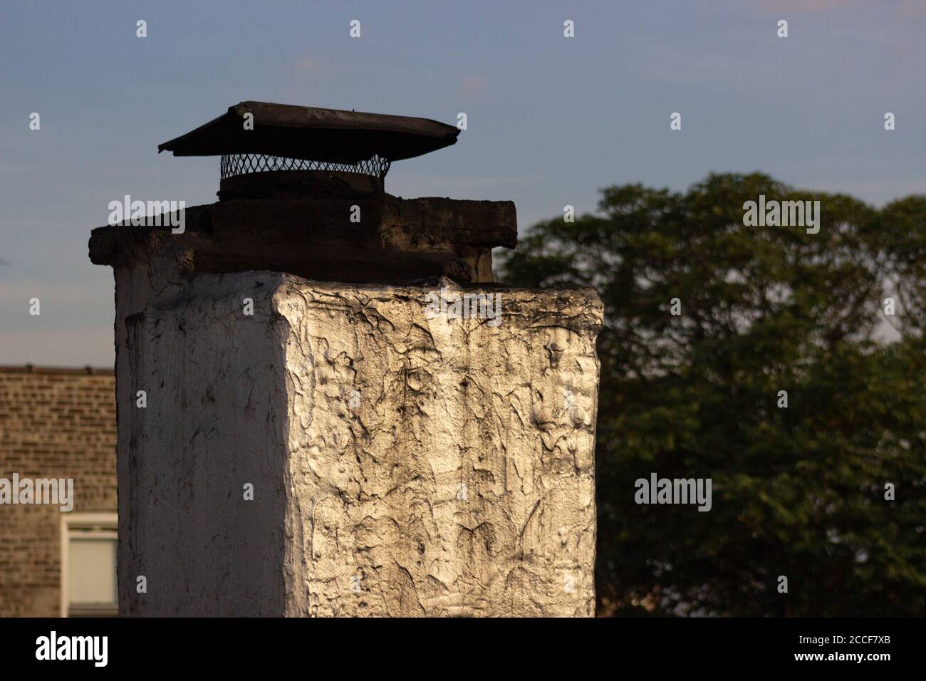 L'estremità arrugginita e tappata di un albero di ventilazione su un tetto di un edificio di appartamenti di New York City, rivestito in carta catrame e invecchiato, gorgogliante, vernice riflettente Foto Stock