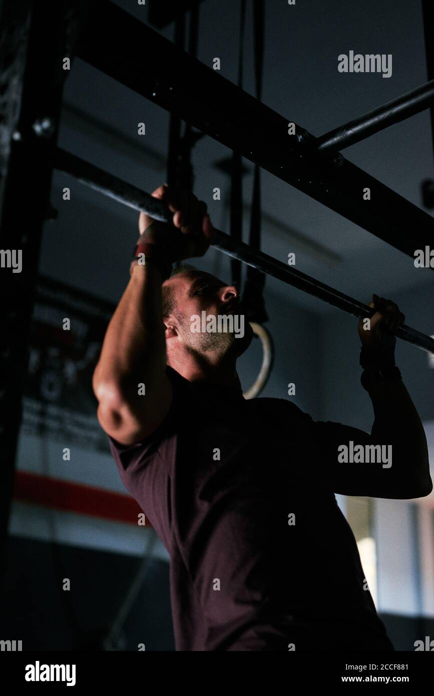 Giovane uomo che lavora in una gabbia in palestra interna Foto Stock