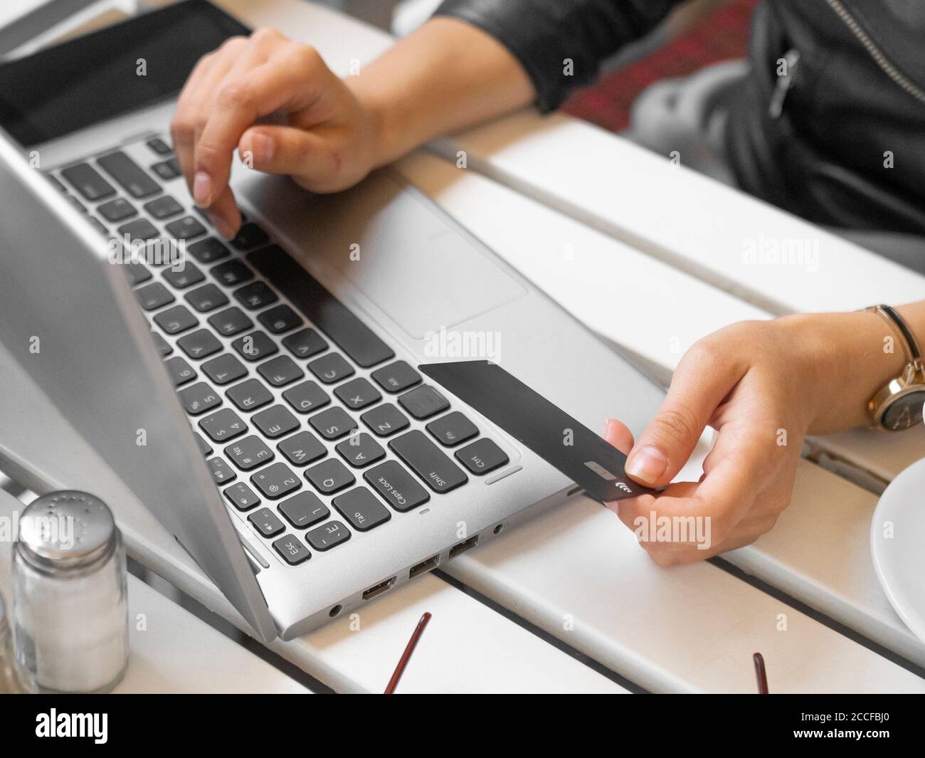 Vista ravvicinata di una donna che usa un computer portatile, una carta di credito e una carta di credito per pagare. Foto Stock
