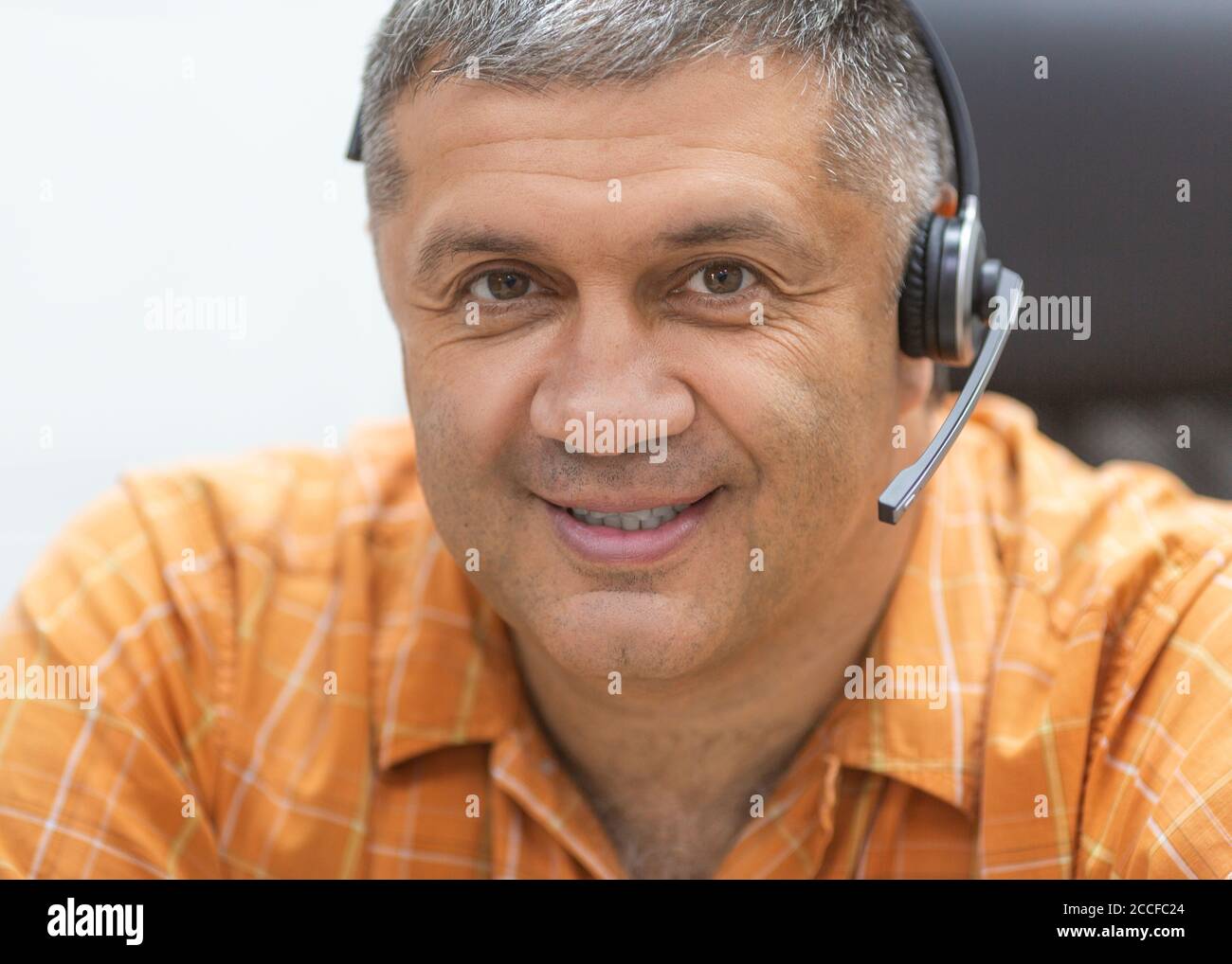Concetto di lavoro online. Uomo sorridente con cuffia che guarda la fotocamera. Primo piano verticale. Foto Stock