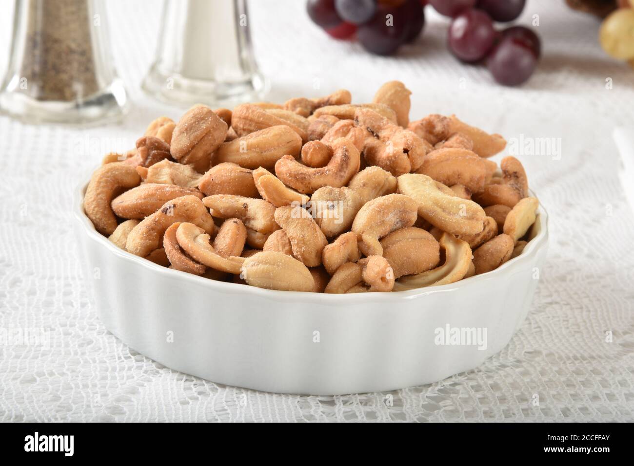 Una ciotola di anacardi salati arrostiti su pizzo bianco tovaglia Foto Stock