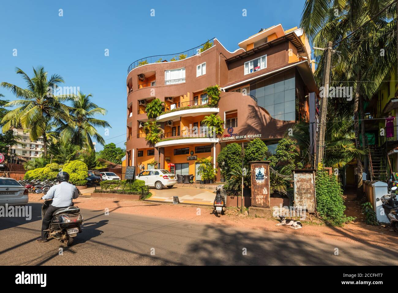 Candolim, Nord Goa, India - 23 novembre 2019: Vista sulla strada di Goa Nord in giornata di sole con auto parcheggiate vicino a negozi turistici e hotel a Candolim, Nord Foto Stock