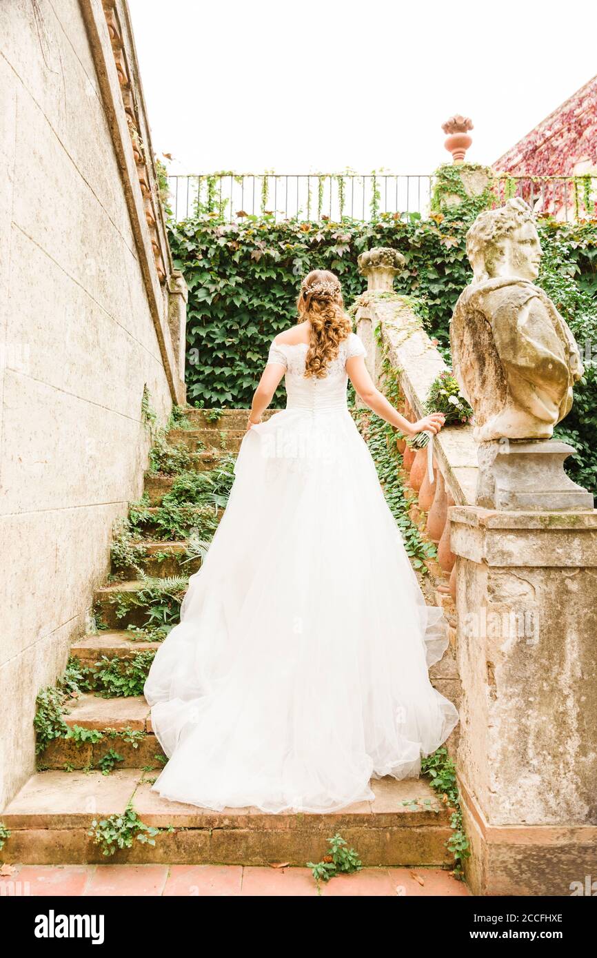 Sposa, matrimonio, giardino, giovane donna, abito da sposa, scale di arrampicata, vista posteriore Foto Stock