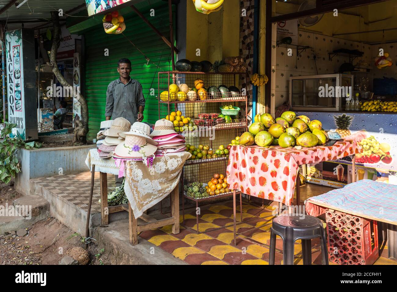 Candolim, Nord Goa, India - 23 novembre 2019: Il venditore locale di strada vende frutta fresca e cappelli a Candolim, Nord Goa, India. Foto Stock