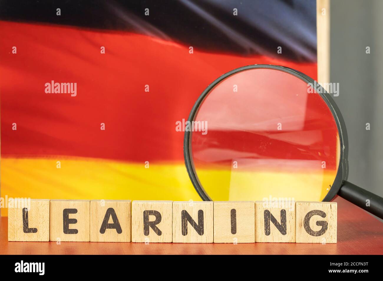 Concetto di apprendimento tedesco, bandiera e parola di apprendimento scritto su legno blocco Foto Stock