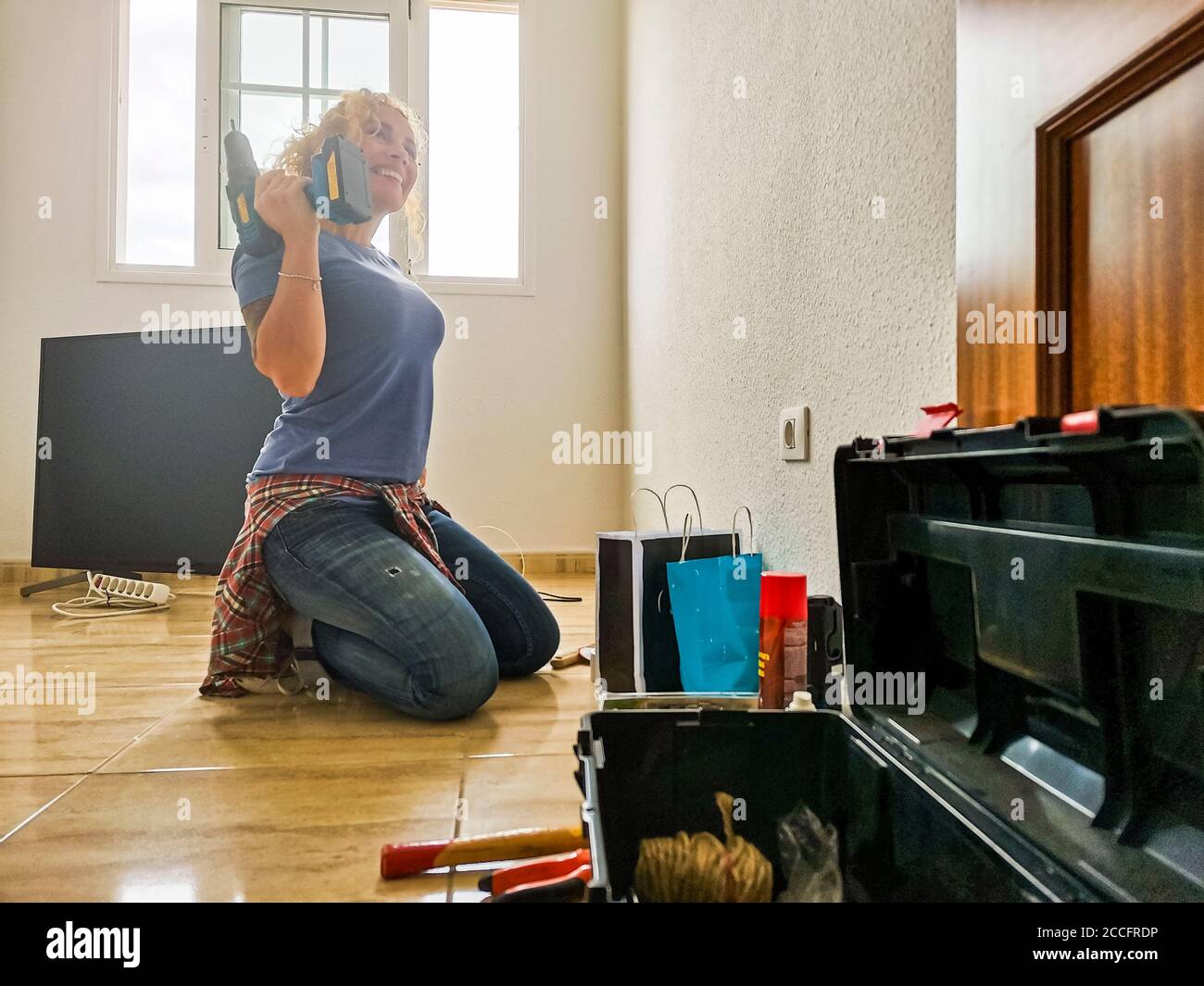 Donna felice e stanca riposano sul pavimento dopo casa lavora durante un mutuo - nuovo concetto di casa e vita - le persone godono di cambiamenti e di lavori fai da te - independde Foto Stock