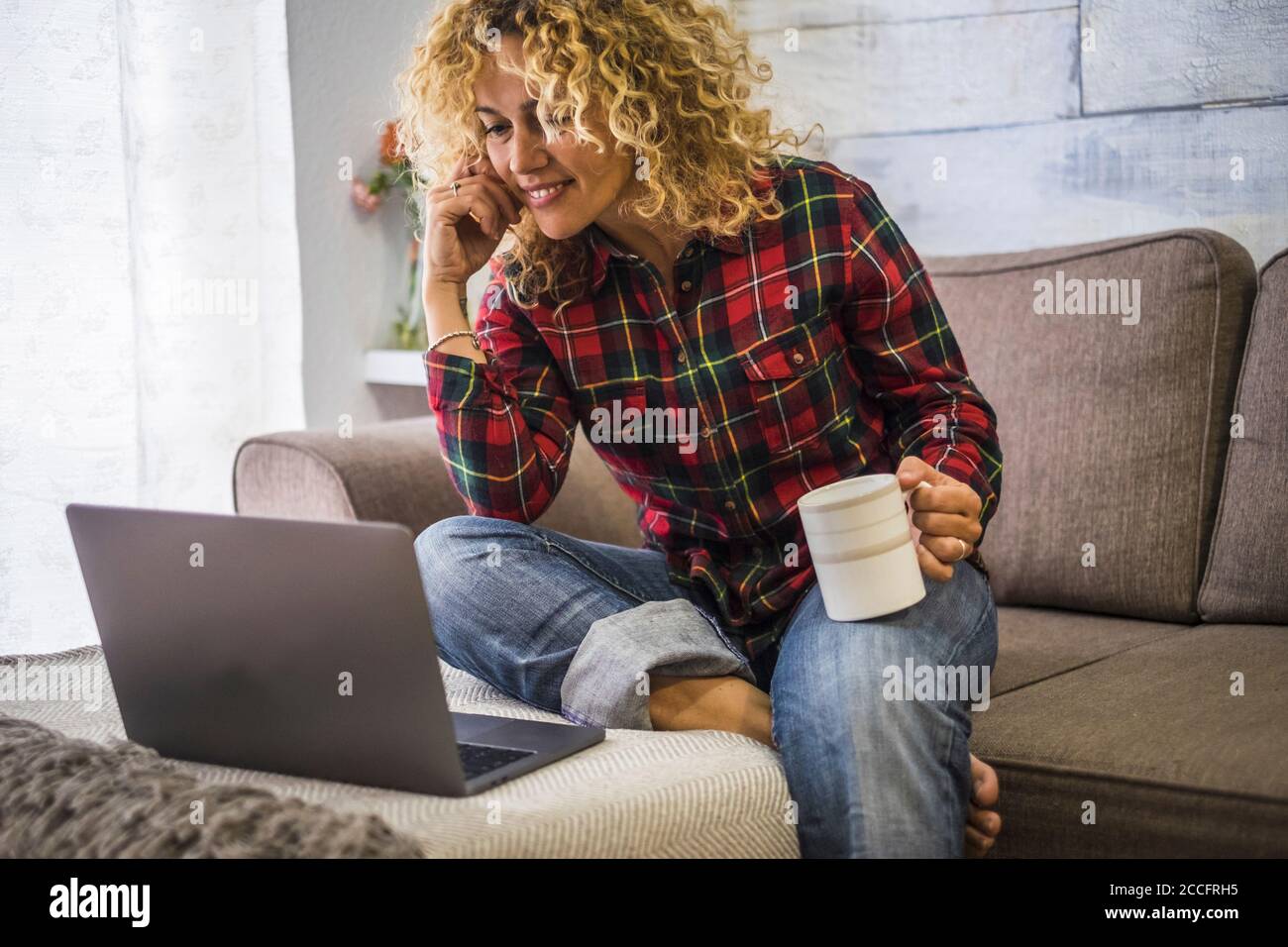 Ritratto di adulto caucasico bella donna a casa uso a. computer portatile seduto sul divano - concetto di video conferenza telefonica e lavoro intelligente - peo Foto Stock