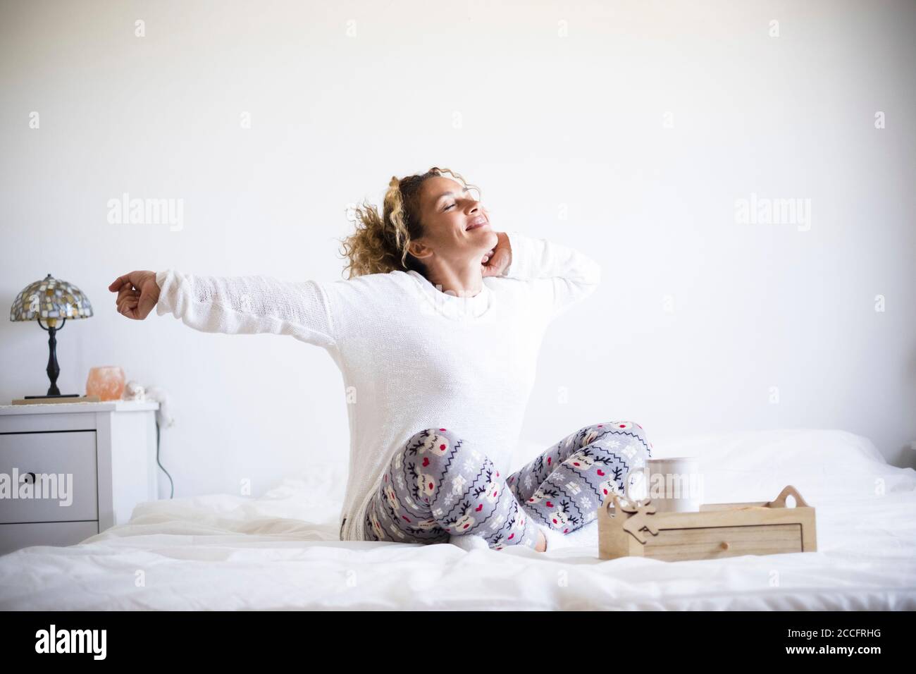 Bella donna svegliarsi al mattino e fare colazione nel letto - la vita da camera da letto per persone sane che si svegliano preparatevi a iniziare una nuova giornata - Foto Stock