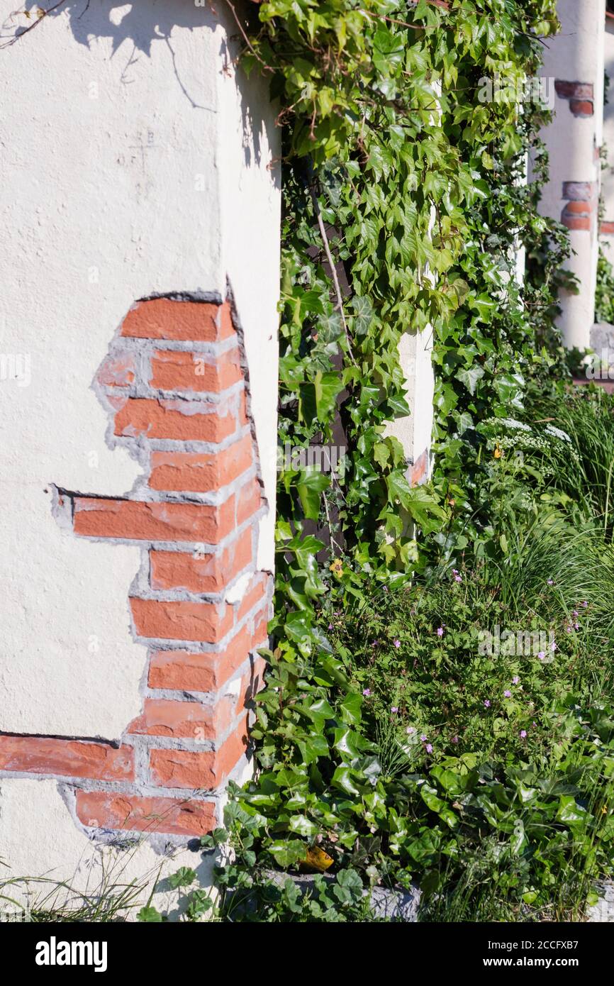Una parete marrone di blocchi di mattoni con una tinta di terracotta e una colonna al centro Foto Stock